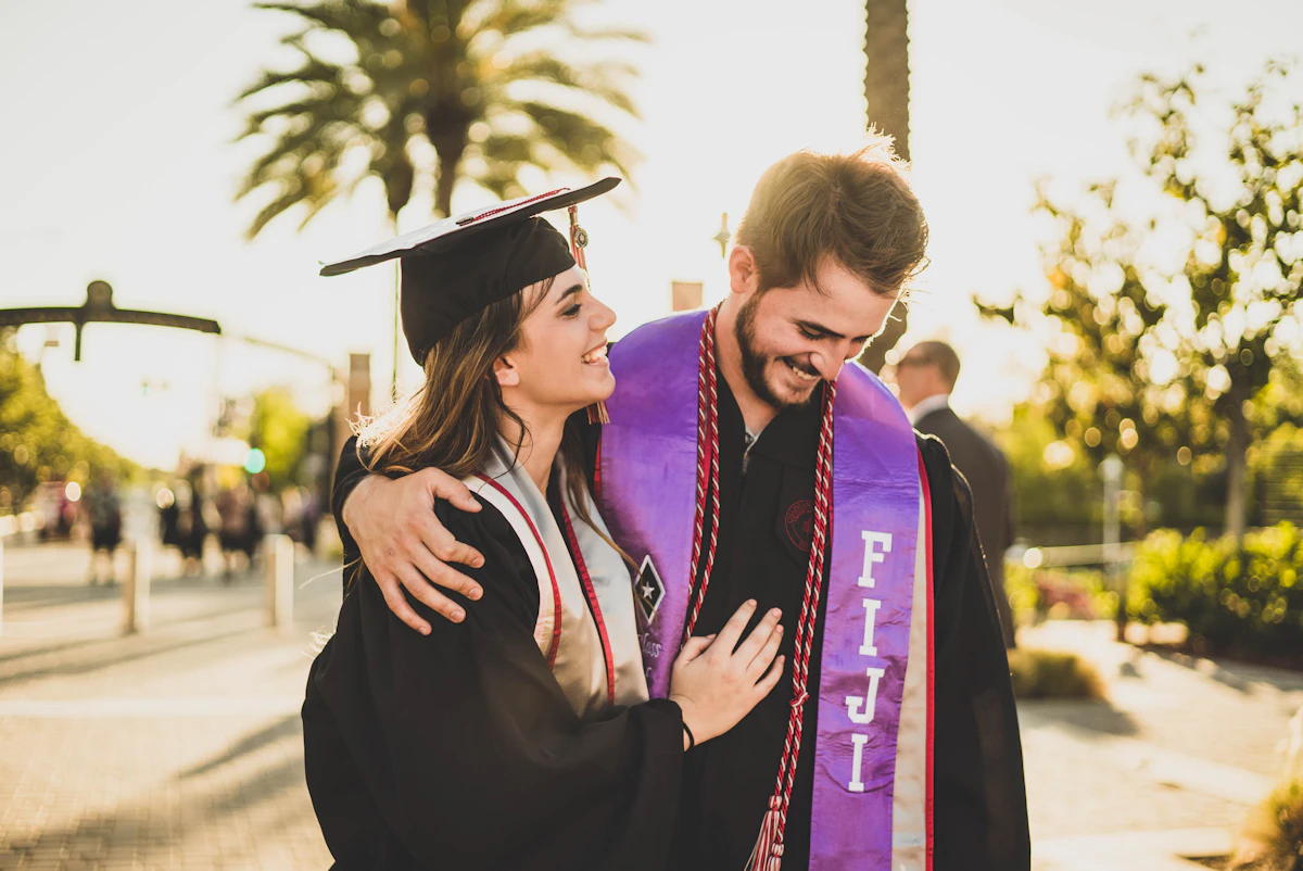 A new graduate in cap and gown sharing a hug